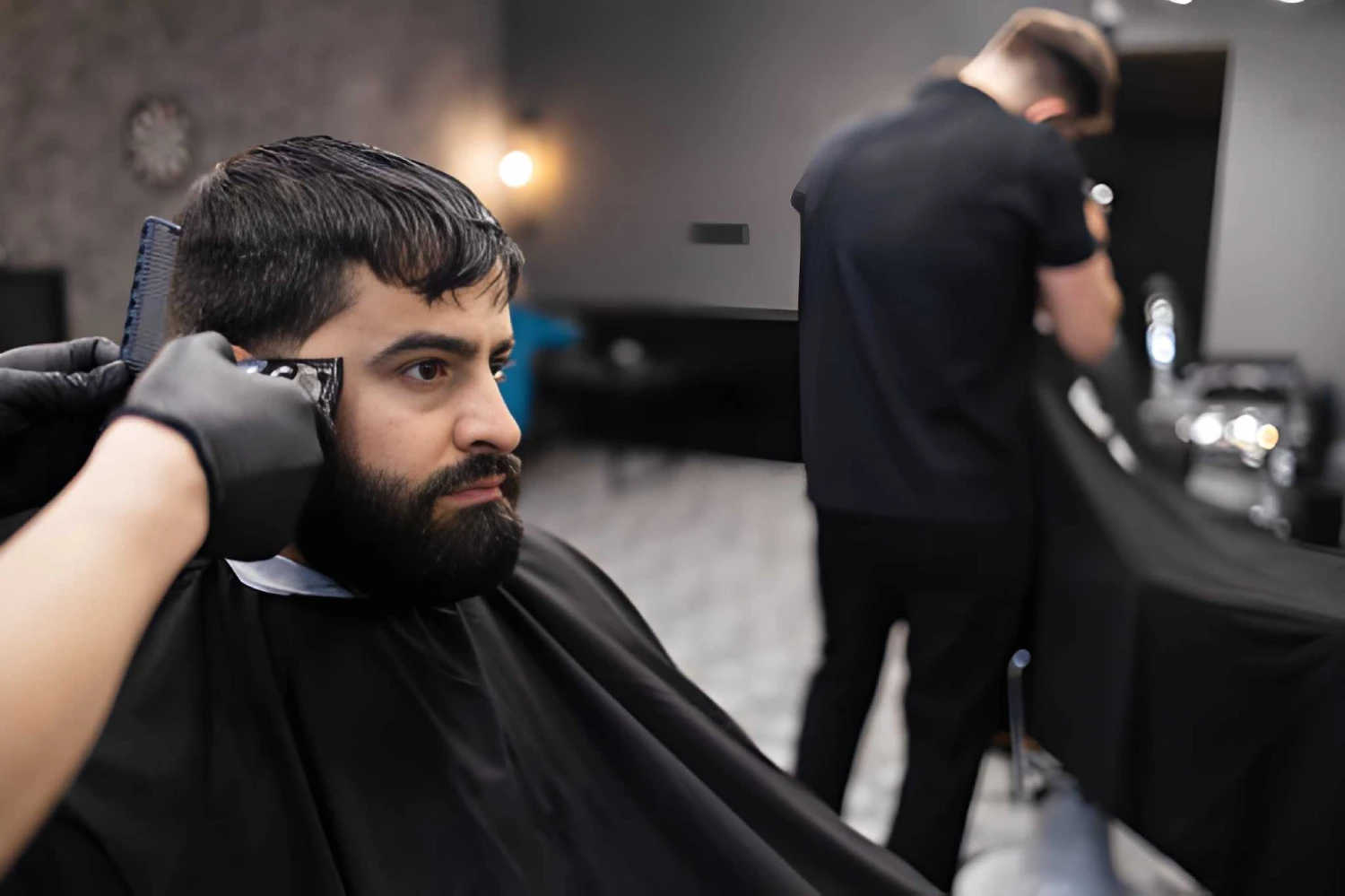 Master cuts hair and beard of men in the barbershop